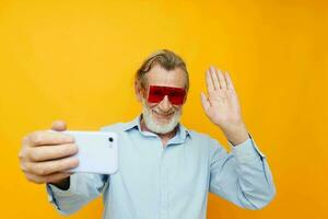 old man posing emotions with phone in hand yellow background photo