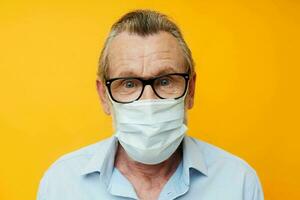 Portrait elderly man with glasses safety medical mask posing yellow background photo