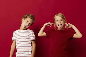 linda preescolar niños sonriente y posando en casual ropa en contra rojo antecedentes foto