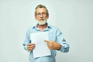 Senior grey-haired man blank sheet of paper gesture hands smile light background photo