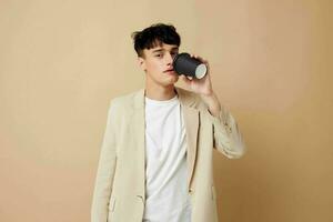 portrait of a young man black disposable glass in the hands of posing fashion light background unaltered photo