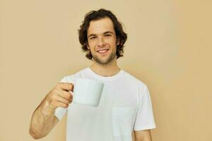 Attractive man in a white T-shirt with a mug in hand isolated background photo