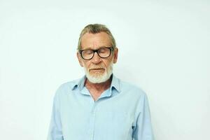 Senior grey-haired man in blue shirts gestures with his hands light background photo