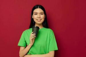 Charming young Asian woman in a green t-shirt a glass of drink fun studio model unaltered photo