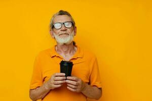 Portrait elderly man in a yellow T-shirt a glass with a drink yellow background photo