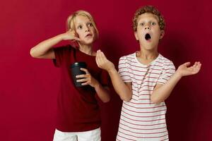 boy and girl disposable glass with drink posing red background photo