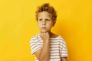 boy with curly hair in a striped t-shirt yellow background photo