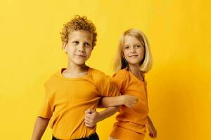 Small children in yellow t-shirts standing side by side childhood emotions yellow background photo