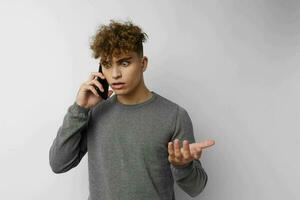 hermoso chico hablando en el teléfono posando emociones aislado antecedentes foto