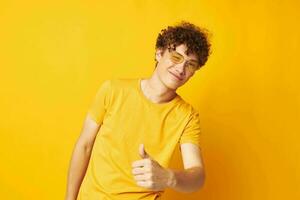 guy with red curly hair yellow t-shirt glasses fashion hand gestures yellow background unaltered photo