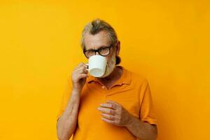 Senior grey-haired man in a yellow t-shirt white mug isolated background photo