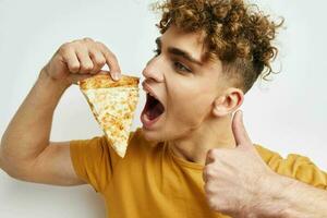 atractivo hombre comiendo Pizza posando de cerca estilo de vida inalterado foto