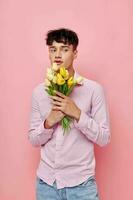 portrait of a young man in a pink shirt with a bouquet of flowers gesturing with his hands model studio photo