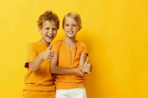 Cute stylish kids in yellow t-shirts standing side by side childhood emotions isolated background unaltered photo