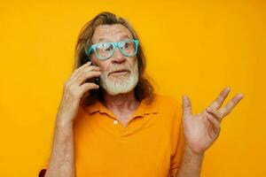 old man in yellow T-shirts and glasses talking on the phone isolated background photo