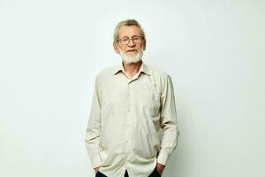 An old man stands on a gray background and looks at the camera with glasses photo