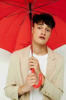 retrato de un joven hombre participación un paraguas en el manos de posando Moda ligero antecedentes inalterado foto