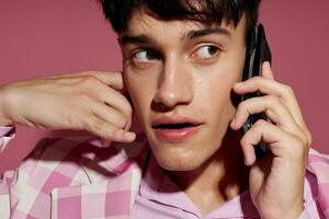 A young man fashionable talking on the phone pink blazer posing studio pink background unaltered photo