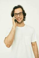 handsome man in a white T-shirt communication by phone light background photo