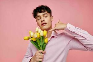 A young man in a pink shirt with a bouquet of flowers gesturing with his hands isolated background unaltered photo