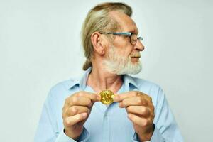 foto de retirado antiguo hombre en azul camisas bitcoin en manos ligero antecedentes