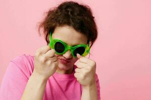 beautiful woman in a pink T-shirt green glasses Youth fashion pink background photo