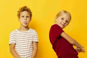 alegre niños en pie lado por lado posando infancia emociones amarillo antecedentes foto