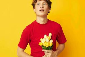 portrait of a young curly man romantic posing with a yellow bouquet of flowers yellow background unaltered photo