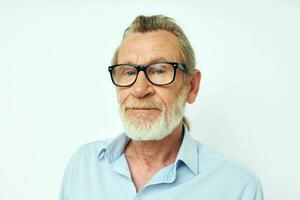 Senior grey-haired man in blue shirts gestures with his hands light background photo