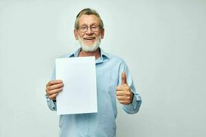 old man in a blue shirt and glasses a white sheet of paper light background photo