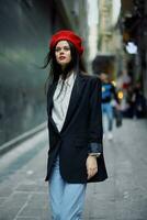 Fashion woman portrait walk tourist in stylish clothes with red lips and red beret walking down a narrow city street, travel, cinematic color, retro vintage style. photo