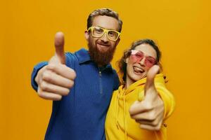 hombre y mujer Pareja sonriente alegremente y torcido con anteojos, en amarillo fondo, símbolos señales y mano gestos, familia disparar, recién casados. foto