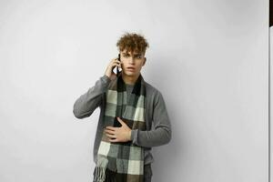 handsome young man in a plaid scarf looking at the phone fashion light background photo