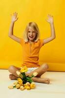 little girl sitting on the floor with a bouquet of flowers yellow background photo