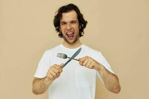 handsome man in a white T-shirt with knife with fork isolated background photo