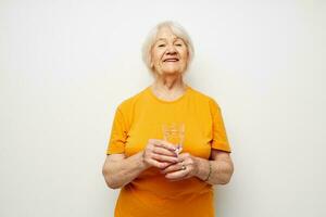 Portrait of an old friendly woman holding a glass of water health light background photo