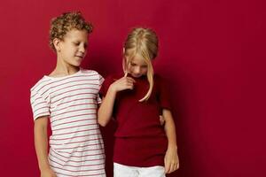 Small children good mood standing next to posing red background photo