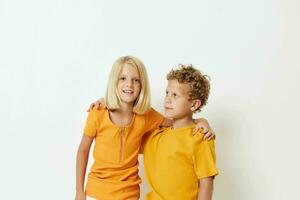 a boy and a girl in yellow T-shirts are standing next to each other on a light background posing photo