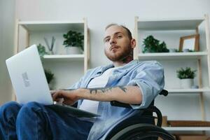Man in wheelchair freelancer working at laptop at home smile, working online, social networks and startup, copy space, social integration, health concept man with disabilities, real person photo