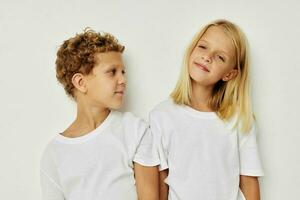 retrato de linda niños en blanco camisetas son en pie siguiente a beige antecedentes foto