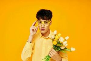 pretty man in yellow glasses with a bouquet of flowers yellow background unaltered photo