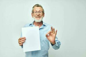 Senior grey-haired man blank sheet of paper gesture hands smile light background photo