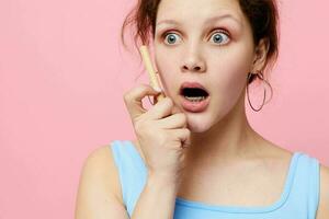 cute girl in a white t-shirt with a pen in his hands emotions pink background photo