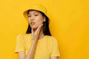 encantador joven asiático mujer en un amarillo camiseta y sombrero posando emociones estilo de vida inalterado foto