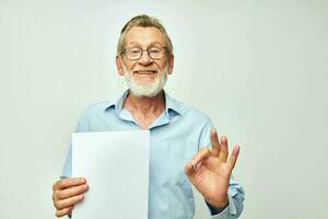 Senior grey-haired man blank sheet of paper gesture hands smile light background photo