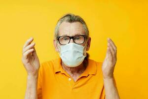 old man medical mask on the face protection close-up yellow background photo