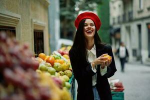 Woman smile with teeth tourist walks in the city market with fruits and vegetables choose goods, stylish fashionable clothes and makeup, spring walk, travel. photo