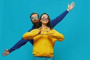 A woman and a man fun couple cranking and showing signs with their hands smiling cheerfully, on a blue background, The concept of a real relationship in a family. photo