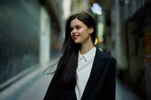 Moda mujer sonrisa con dientes retrato turista en elegante ropa en chaqueta con rojo labios caminando abajo estrecho ciudad calle volador cabello, viajar, francés estilo, cinematográfico color, retro Clásico estilo. foto