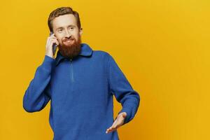 Portrait of a man smiling in a blue sweater on a yellow background copy space, space for text photo